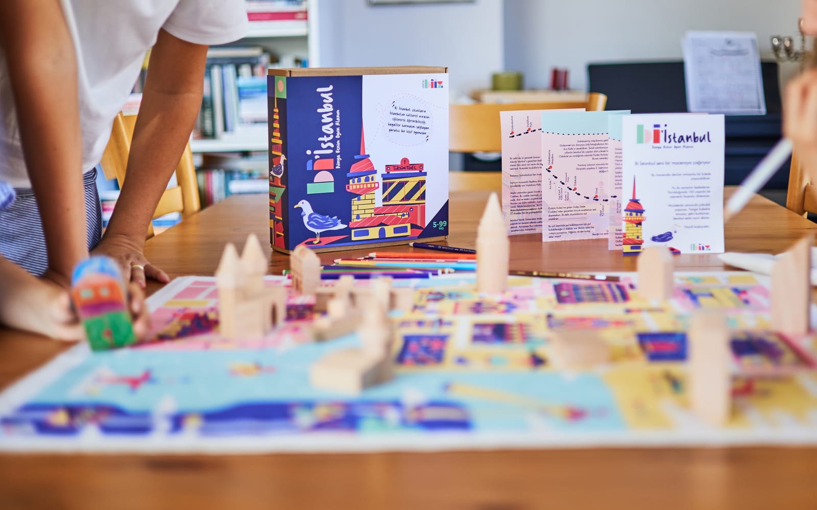 Atelier Biiz — masa üzerinde renkli kapaklı oyun broşürleri ve İstanbul temalı oyun parçaları