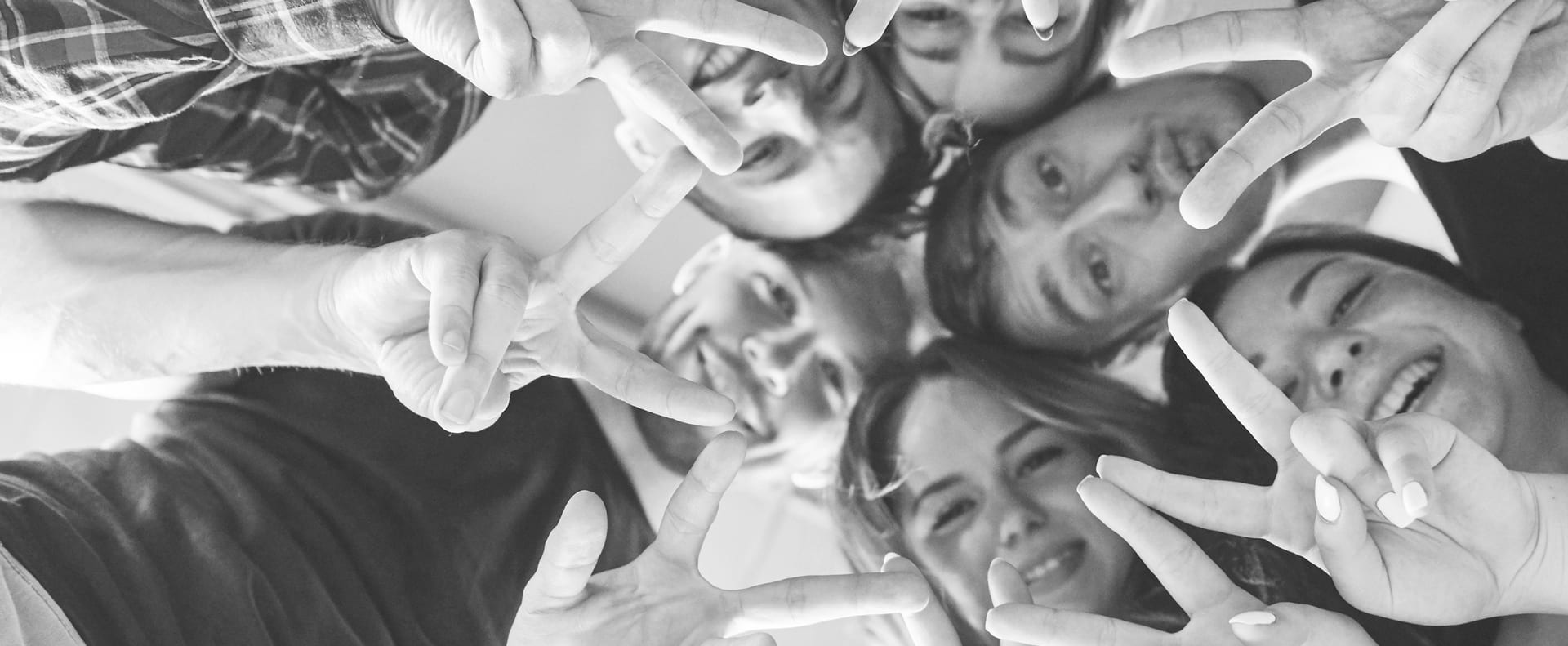 Carrier HR — anahtar görsel: zafer işareti yapan ve gülümseyen genç ekip üyelerinin yukarıdan çekilmiş siyah-beyaz fotoğrafı